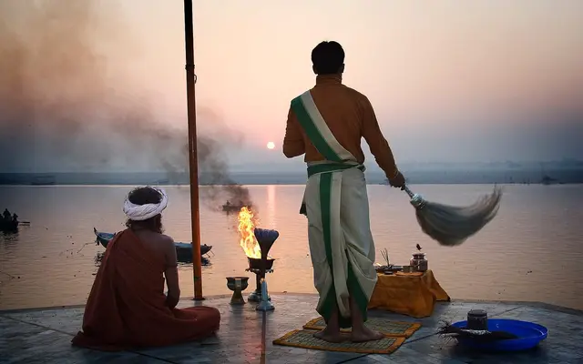 Priests performing dawn fire ritual on a Varanasi ghat as the sun rises