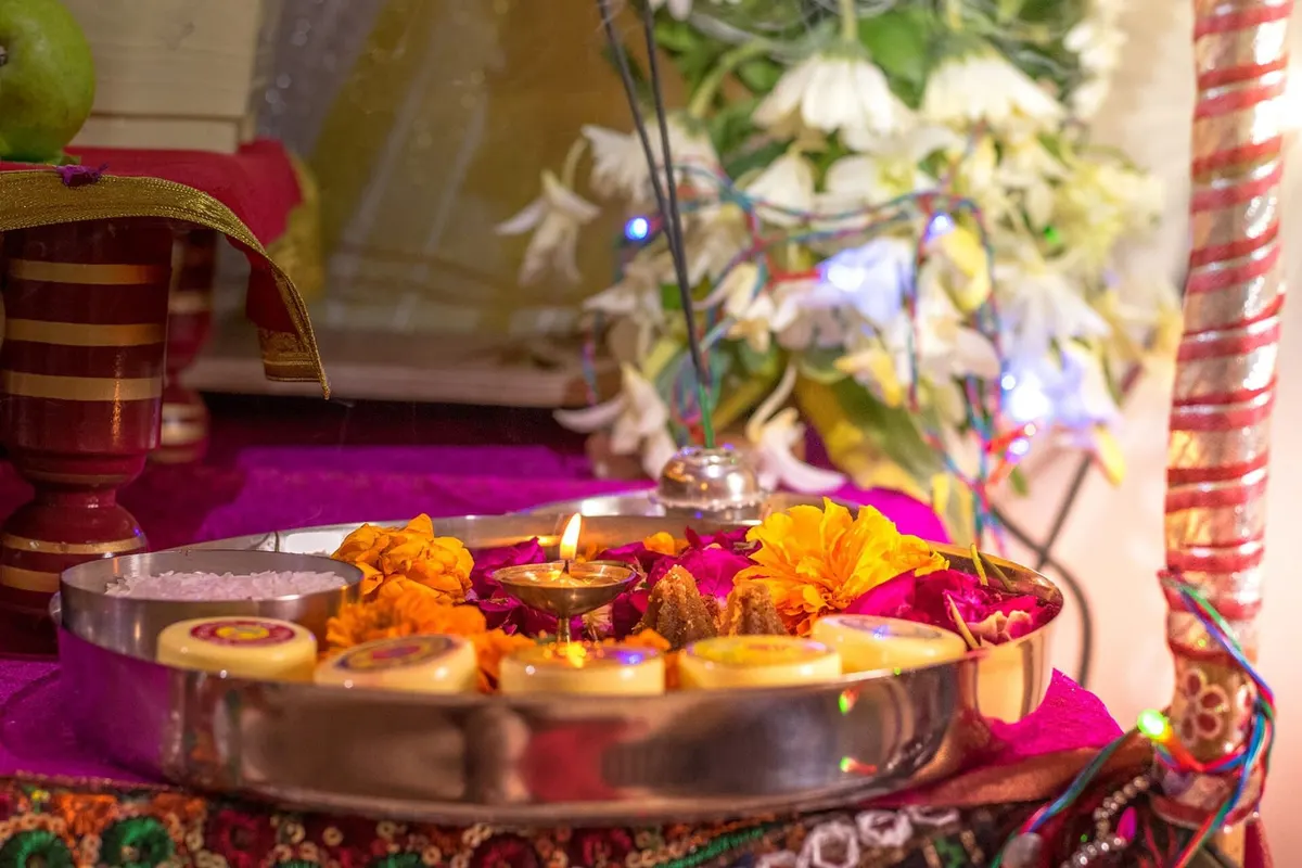 Home puja thali with diya, marigolds, sweets and flowers before the altar