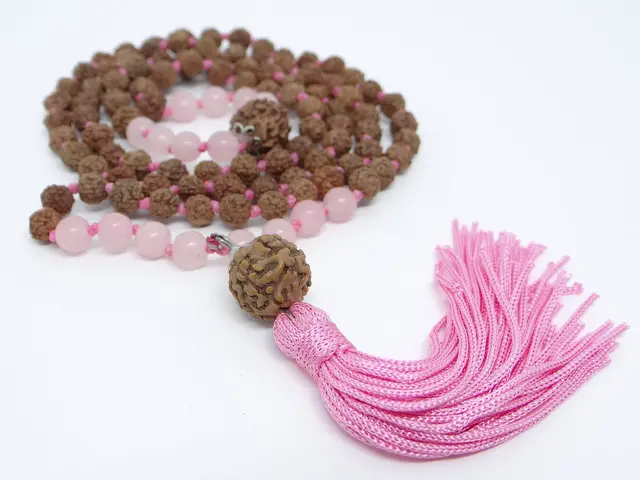 Rudraksha and rose quartz japa mala with pink tassel on white background